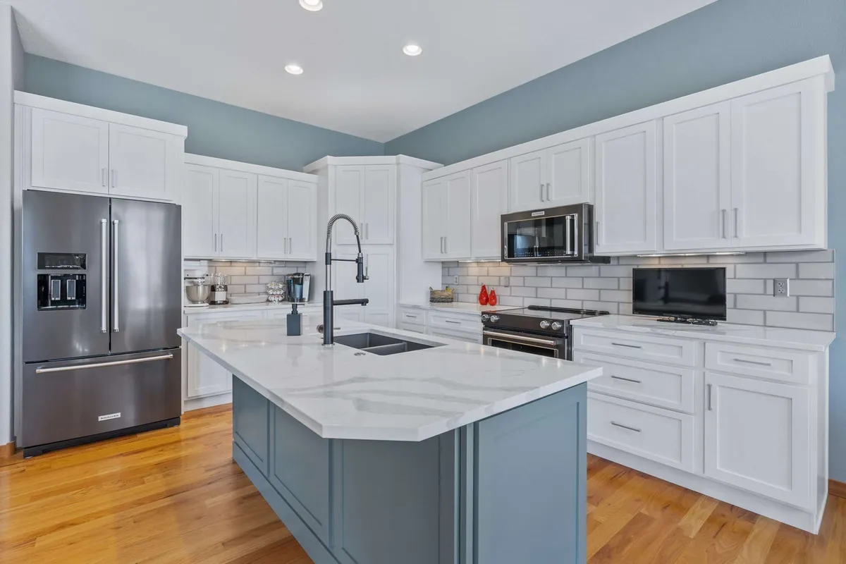 The same kitchen with white cabinets and a blue-grey island