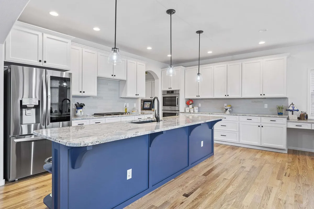 The same kitchen with white cabinets and a navy island